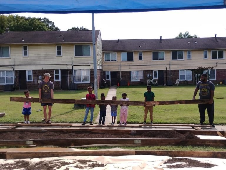 Matthew and Kawan with Robinwood kids holding up a board for a garden bed