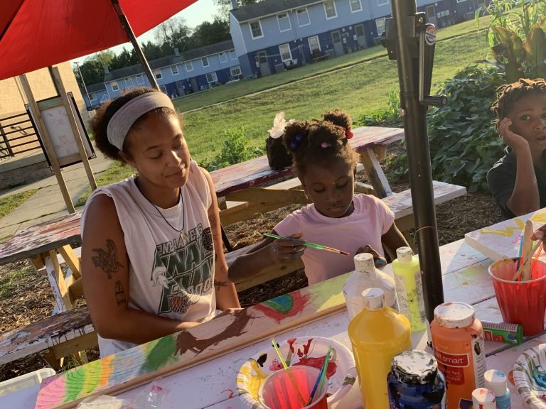 Two young artists painting panels for a garden box