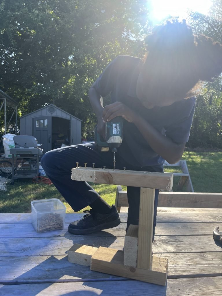 Rayell using a drill on a build at the farm