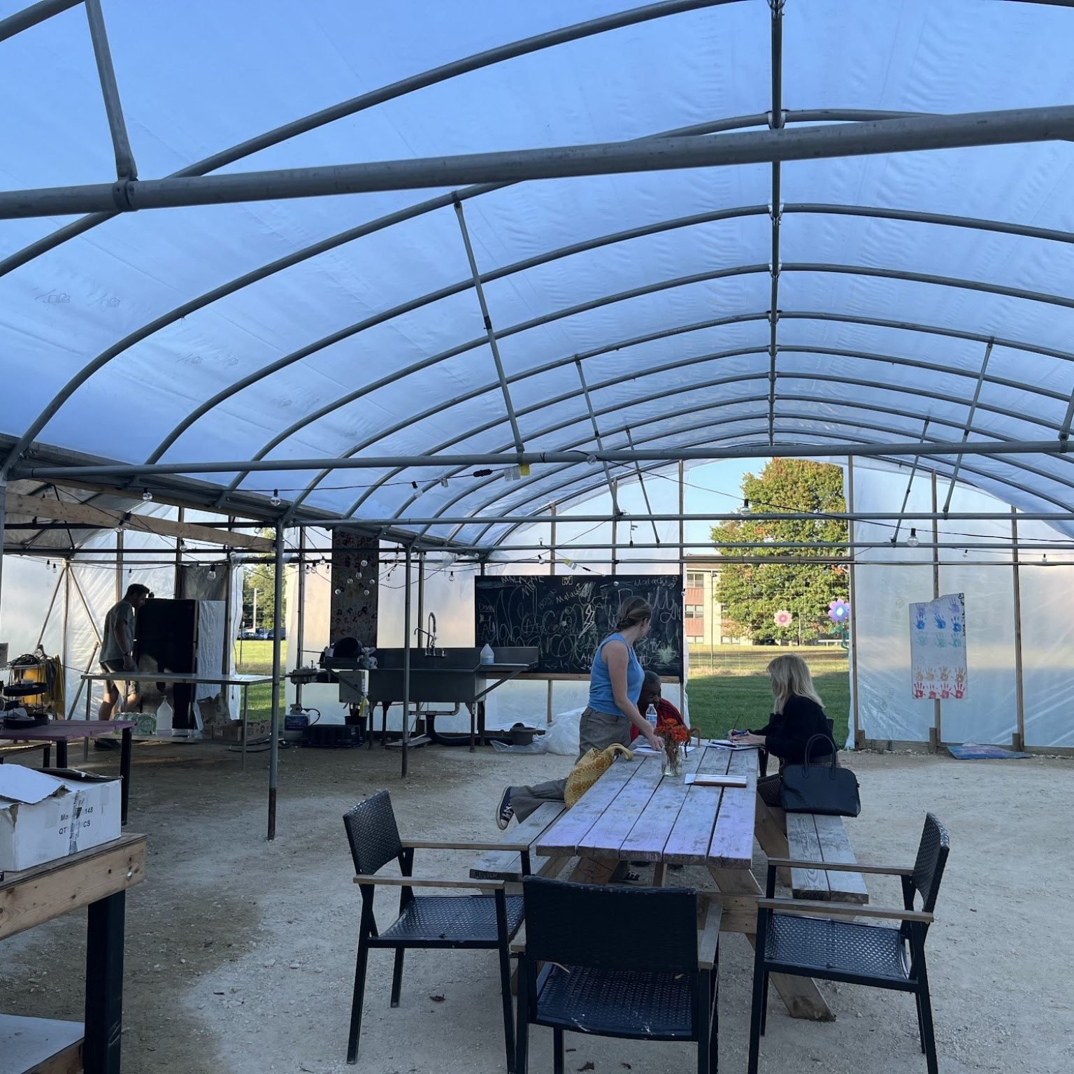 Inside the Eastport Community Farm greenhouse, with the kitchen sink, chalkboard and picnic tables