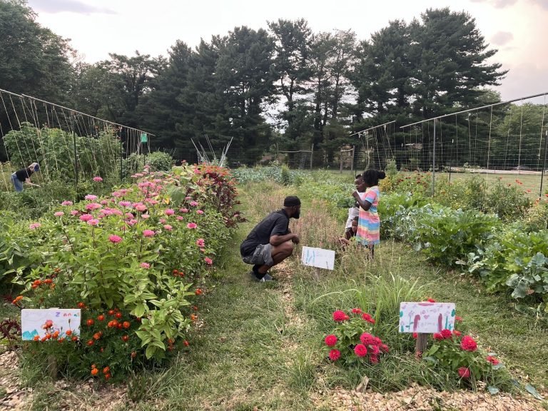 Kareem in the herb and flower garden with two Growing Leaders
