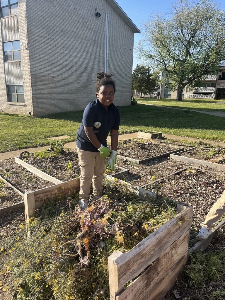 A Growing Leader filling a compost pile and standing on top of it