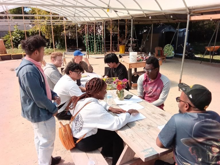 Young people reading and talking around a picnic table at the farm