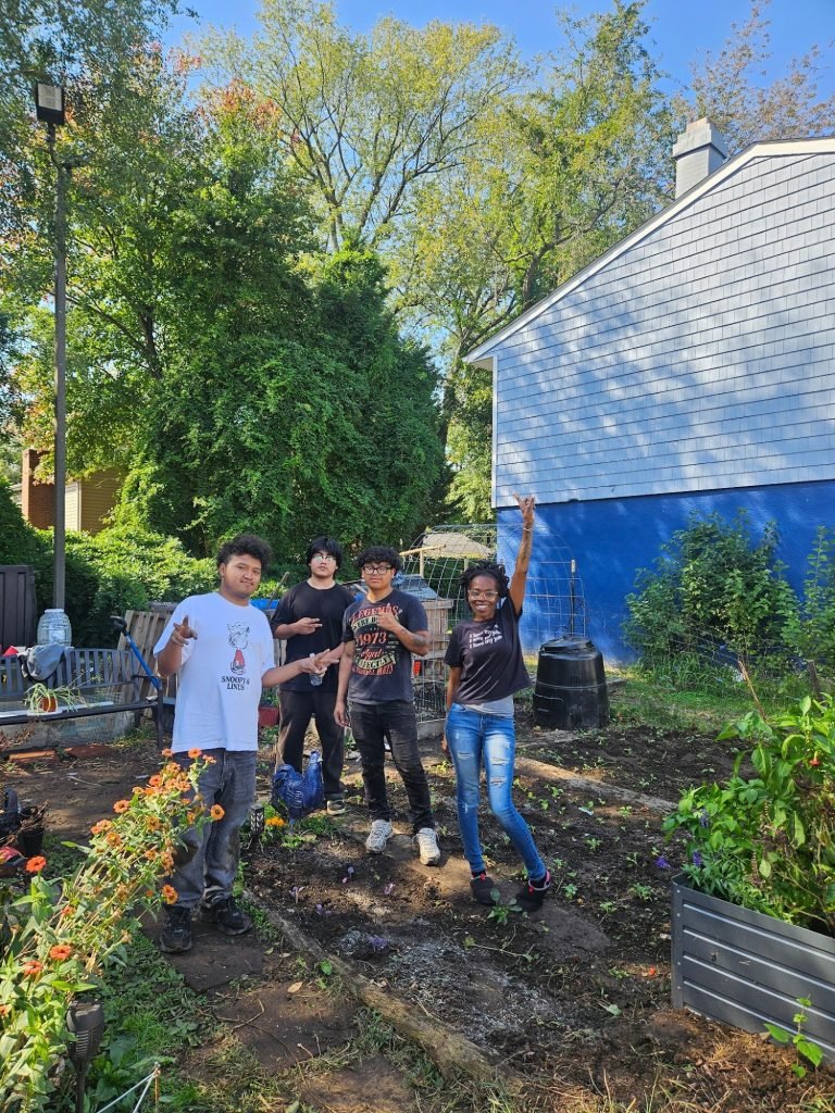 Service Year members with Heaven White in her garden, where they planted kale together